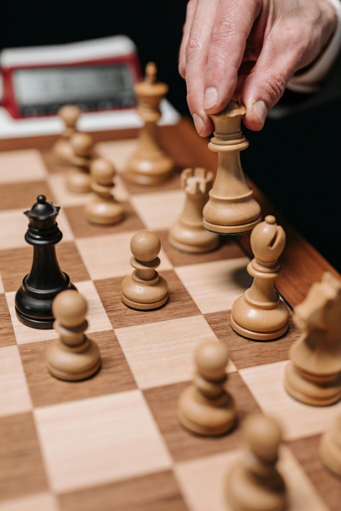 A close-up of a hand making a chess move during a game, emphasizing strategy and concentration.